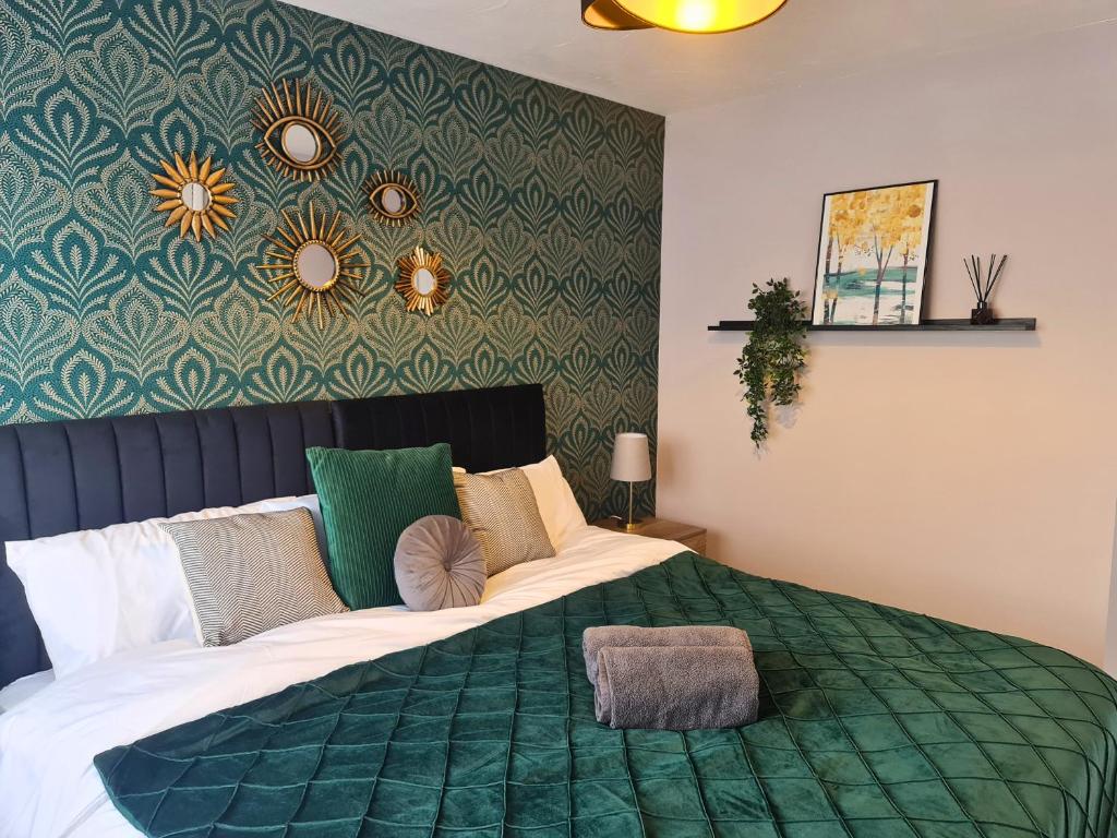 a bedroom with a large bed with a green comforter at Cozy 2 bedroom house with parking, Aylesbury in Buckinghamshire