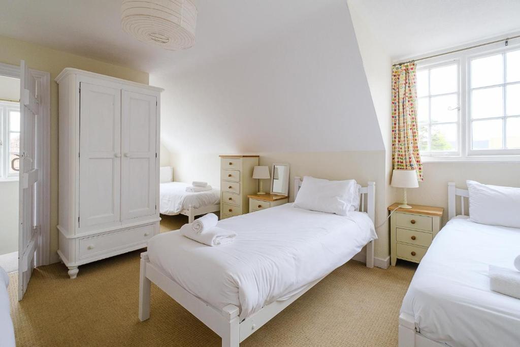 a white bedroom with two beds and a window at 9 Whinlands in Thorpeness