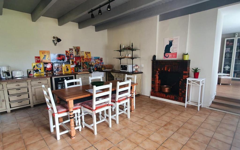 eine Küche mit einem Tisch und Stühlen sowie einem Kamin in der Unterkunft Maison bretonne au cœur d'un petit hameau 