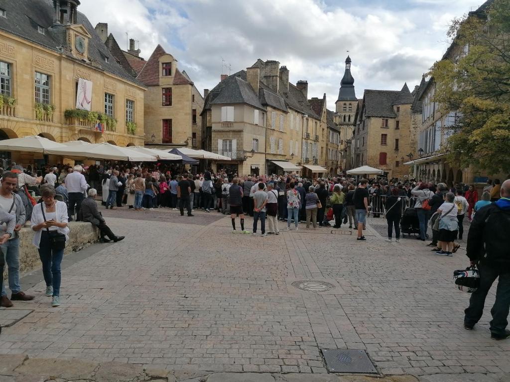 Une foule de gens marchant dans une rue d'une ville dans l'établissement Le p'tit appart, à Sarlat-la-Canéda