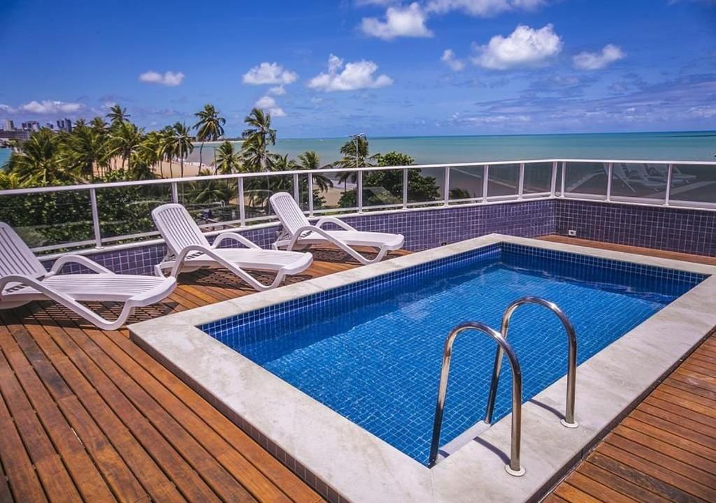 - une piscine sur une terrasse avec des chaises et l'océan dans l'établissement Atlântico Sul - Cabo Branco, à João Pessoa