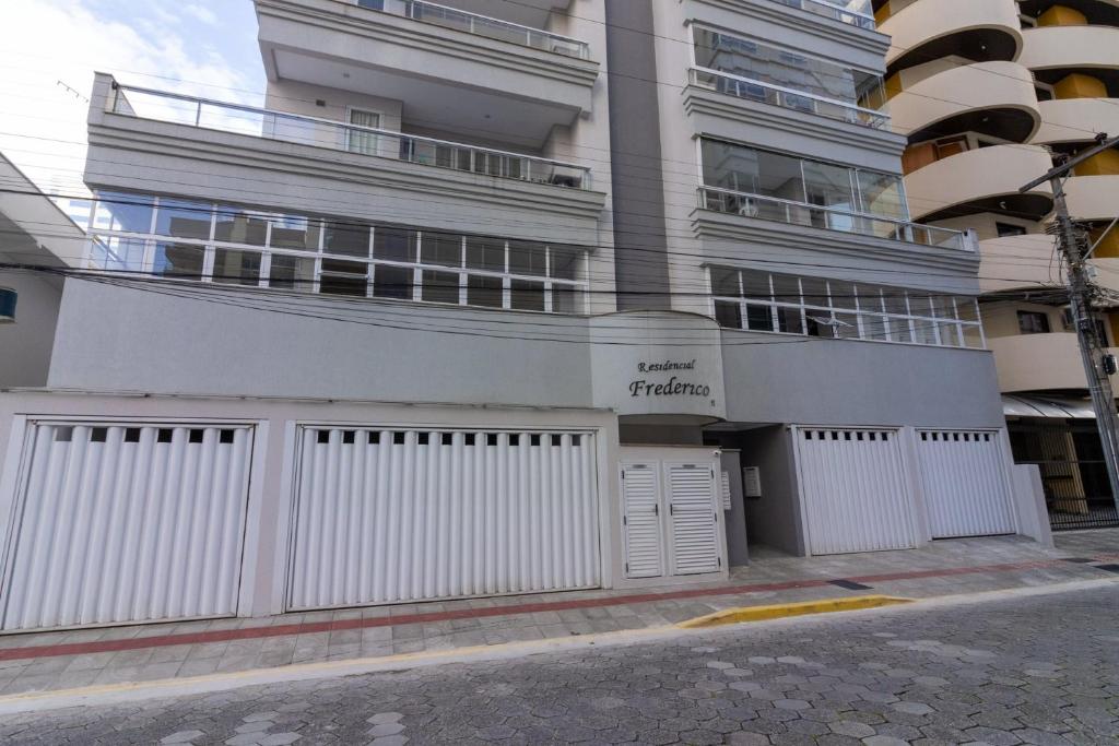 un edificio de apartamentos blanco con una valla blanca en Frederico, en Meia Praia