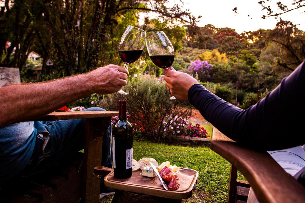 モンテ・ヴェルデにあるPousada Vila Suiça - Monte Verdeのピクニックテーブルでワインを飲んでいる2人