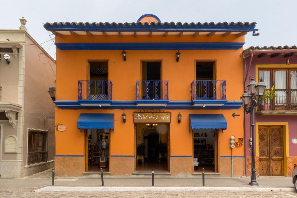 an orange building with blue balconies on a street at Hotel del Parque Naolinco in Naolinco