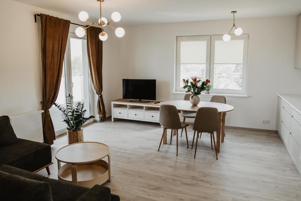 een witte woonkamer met een tafel en stoelen bij Soft Loft in Szczecinek