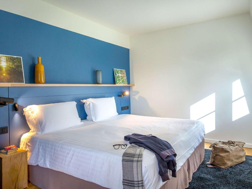 a bedroom with a large bed with a blue wall at Mercure Chantilly Resort & Conventions in Chantilly
