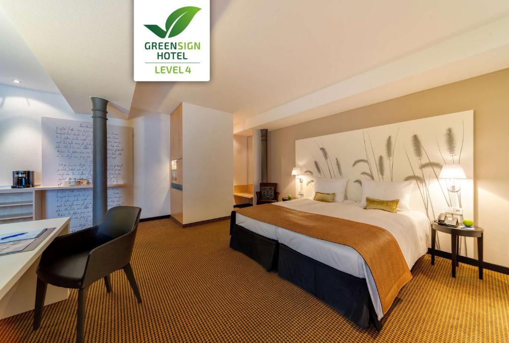 una camera d'albergo con un grande letto e una scrivania di nestor Hotel Stuttgart-Ludwigsburg a Ludwigsburg