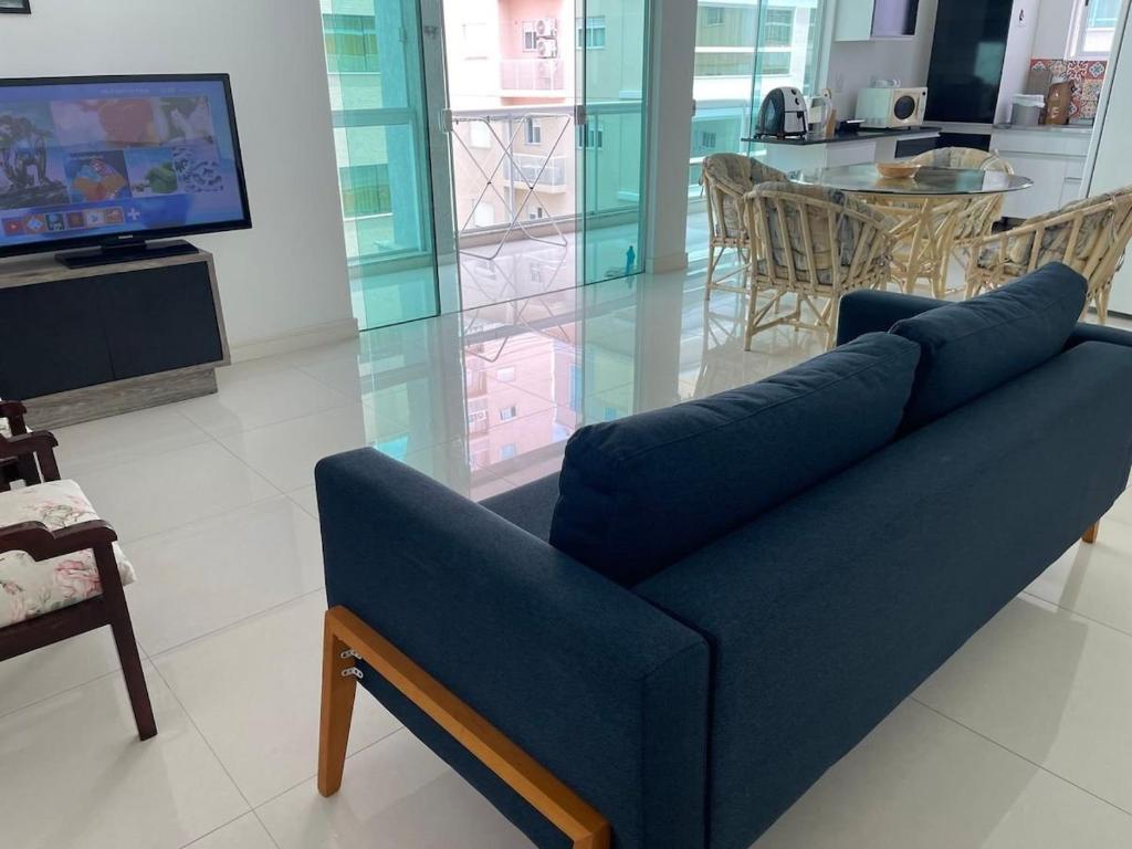 un sofá azul en la sala de estar con TV en Supremo, en Meia Praia