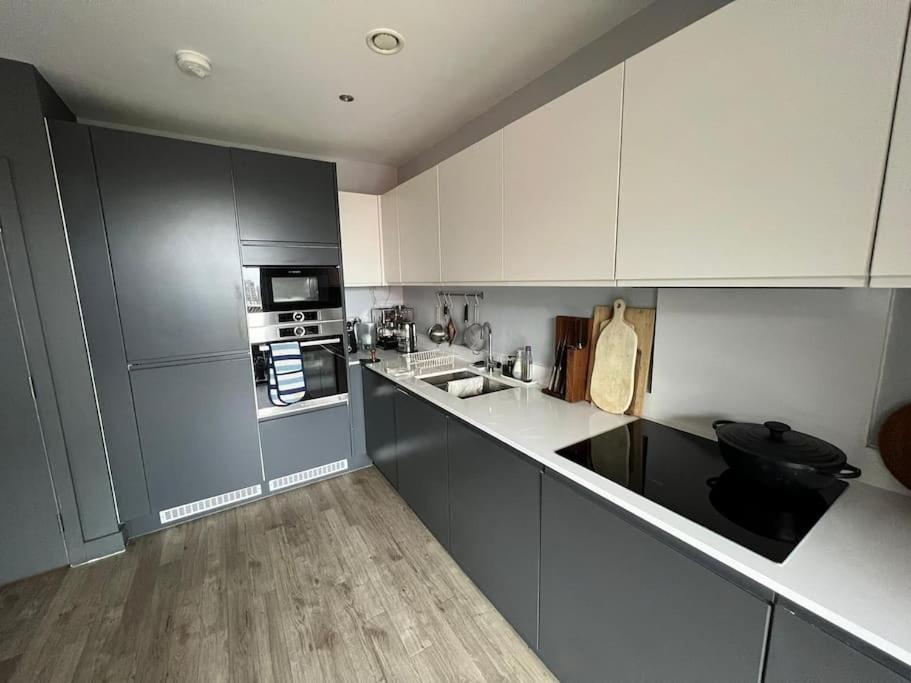 a kitchen with gray and white cabinets and appliances at East London's hidden gem - relax after sightseeing in a huge canal view balcony in London
