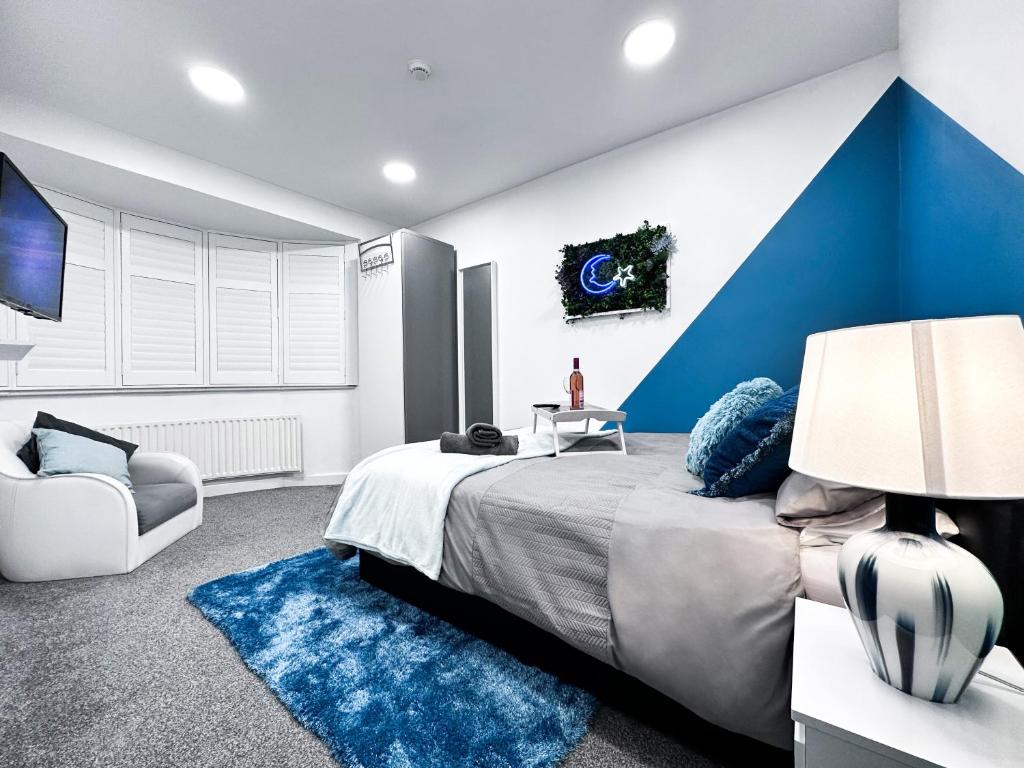 a bedroom with a large bed with a blue accent wall at Cosy Contemporary Apartment - Brimsdown, Enfield in Enfield Lock