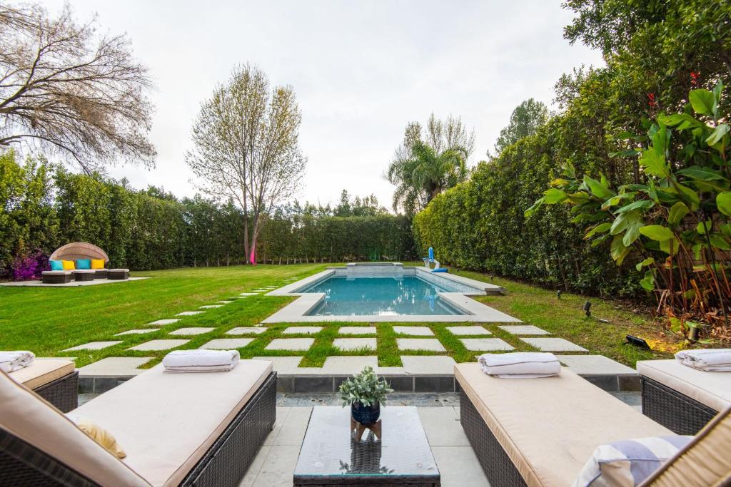 a backyard with a swimming pool and a lawn at Woodland Hills Paradise Resort Style Home in Los Angeles