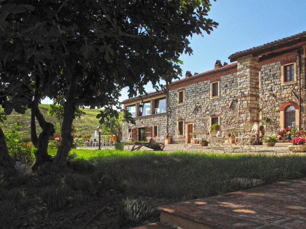 a stone house with a tree in front of it at B&B Tenuta il Galletto in Casale Monferrato
