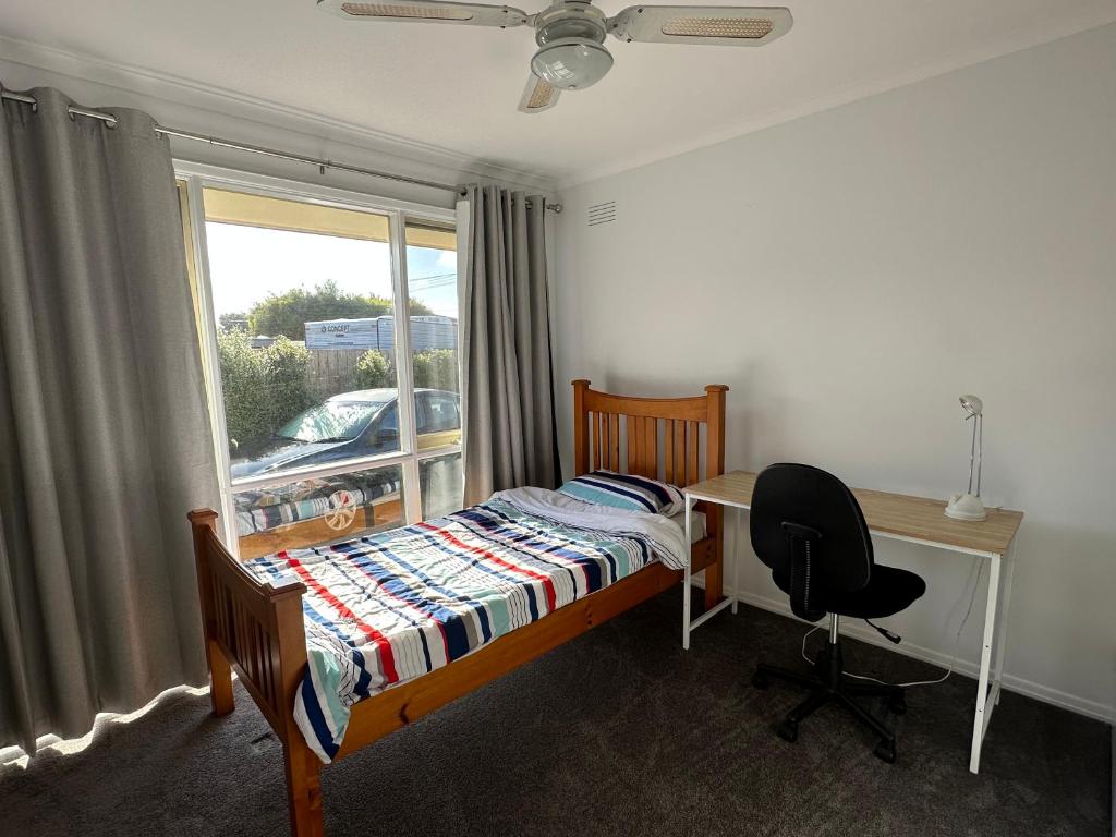 a bedroom with a bed and a desk and a window at Comfy bed quiet neighbourhood in Grovedale