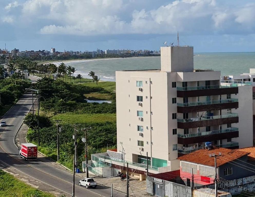 a tall white building next to a road next to the ocean at Vela e Mar in Nossa Senhora do Livramento