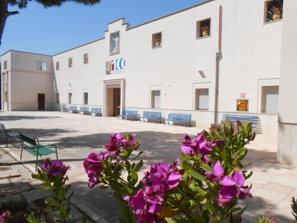 un edificio con flores púrpuras delante de él en Sacro Cuore Opera Don Guanella en Torre Canne