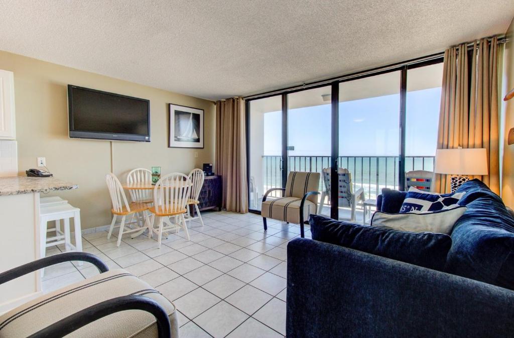 uma sala de estar com um sofá e uma mesa com cadeiras em 0610 Smooth Sailing by Atlantic Towers em Carolina Beach