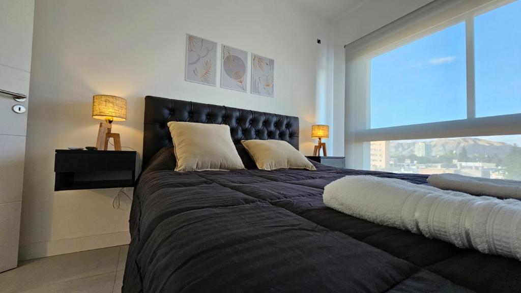 a bedroom with a large black bed with two lamps at MaJo Apart in San Luis