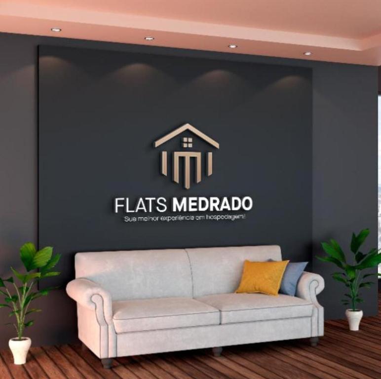 a couch in a room with a wall with a logo at FlatsMedrado Hotel in Confresa