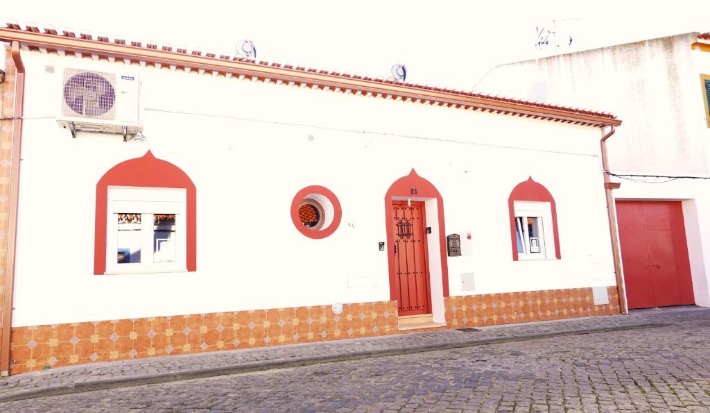 a white building with red doors on a street at Aladin Comfort Country T3 in Campinho