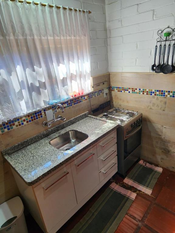 a small kitchen with a sink and a stove at Chalés Monte Verde in Monte Verde