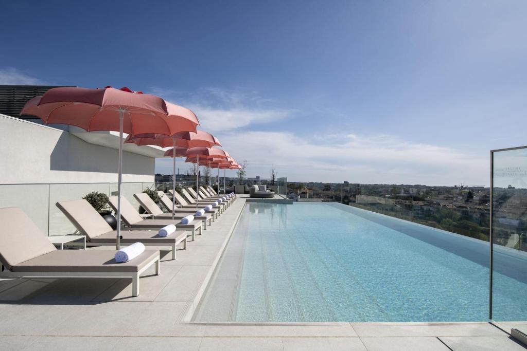 una piscina con sillas y sombrillas en un edificio en Renaissance Porto Lapa Hotel, en Oporto