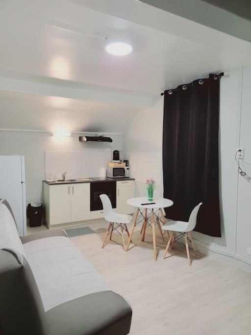 een woonkamer met een tafel en stoelen en een keuken bij Cosy appartement Pierrefitte sur seine proche Paris "Appart'1" in Pierrefitte-sur-Seine
