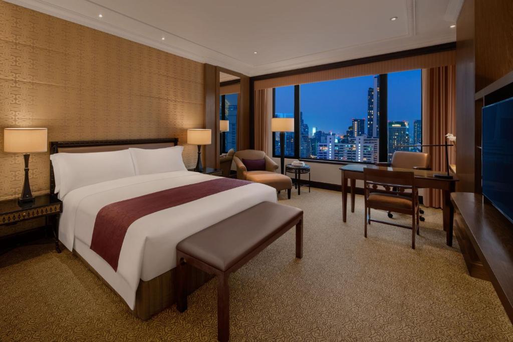 a bedroom with a bed and a desk and a large window at Sheraton Grande Sukhumvit, a Luxury Collection Hotel, Bangkok in Bangkok