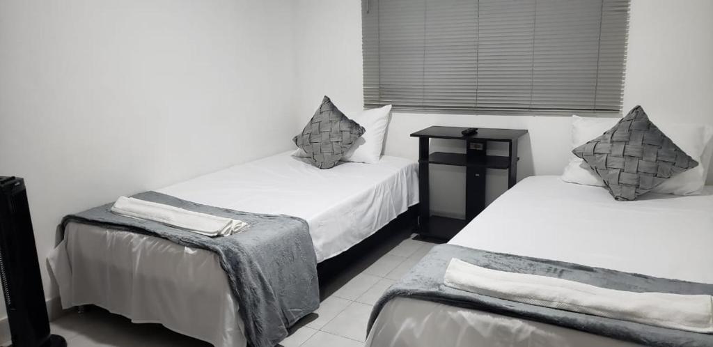 卡利的住宿－Hotel Nueva Tequendama，一间设有两张床和一张桌子的房间