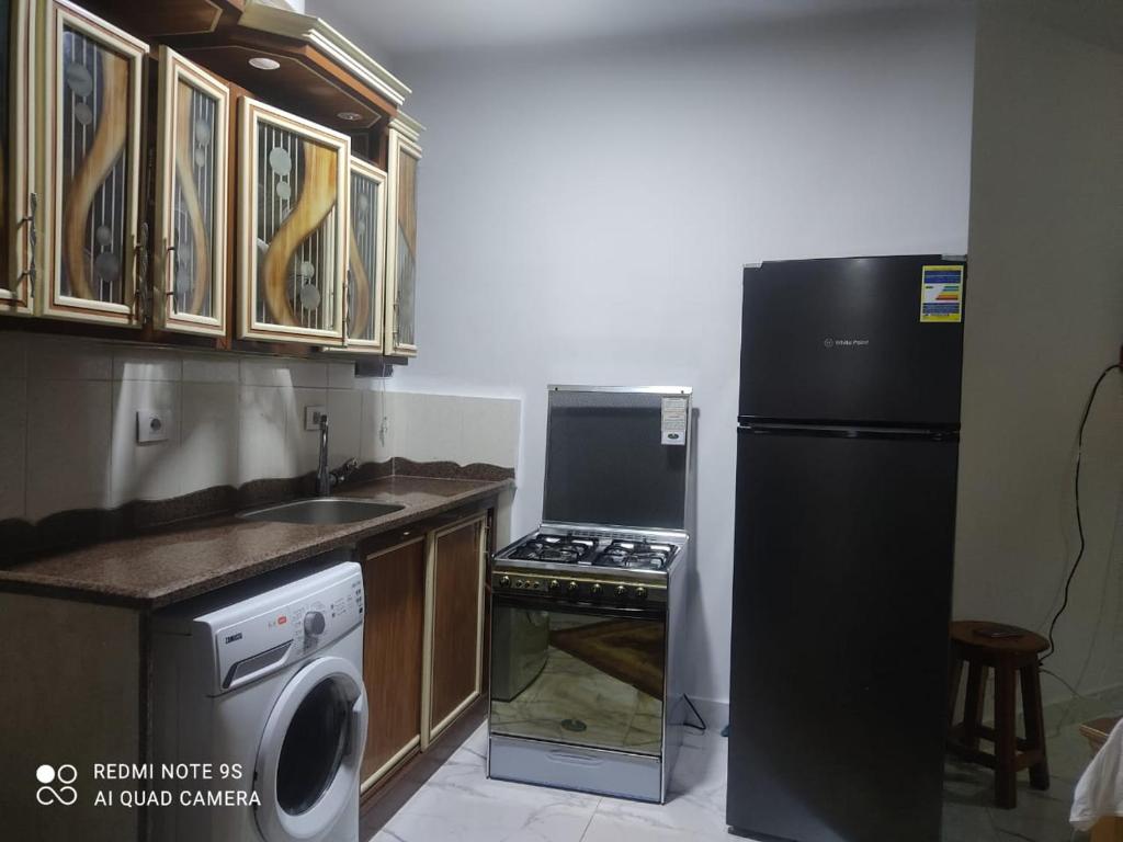 eine Küche mit einem schwarzen Kühlschrank und einem Geschirrspüler in der Unterkunft بورتو سعيد وحدات in `Ezbet Shalabi el-Rûdi