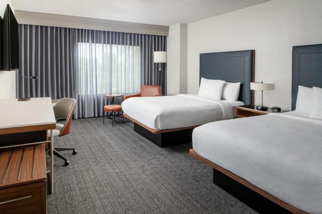 Courtyard by Marriott New Orleans Metairie في ميتايري: غرفة فندقية بسريرين ومكتب