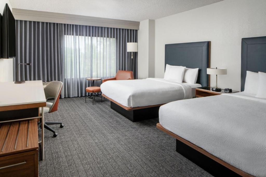 a hotel room with two beds and a desk at Courtyard by Marriott New Orleans Metairie in Metairie
