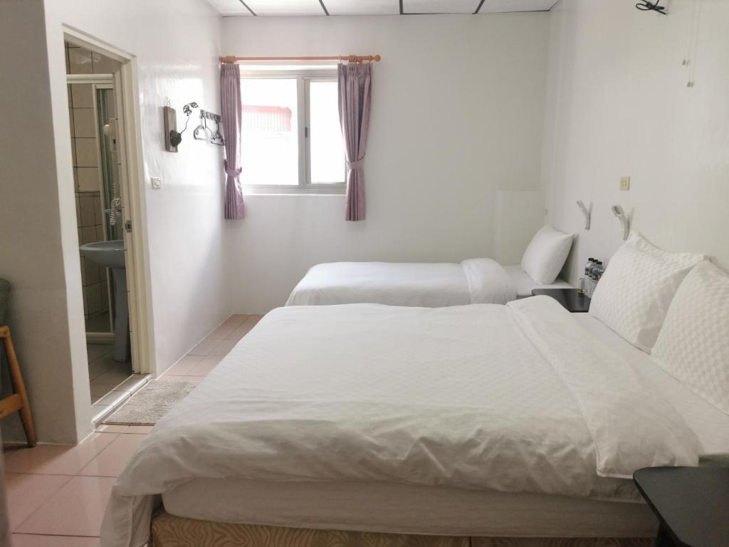 a white bedroom with two beds and a window at Alishan Tea Homestay in Leye