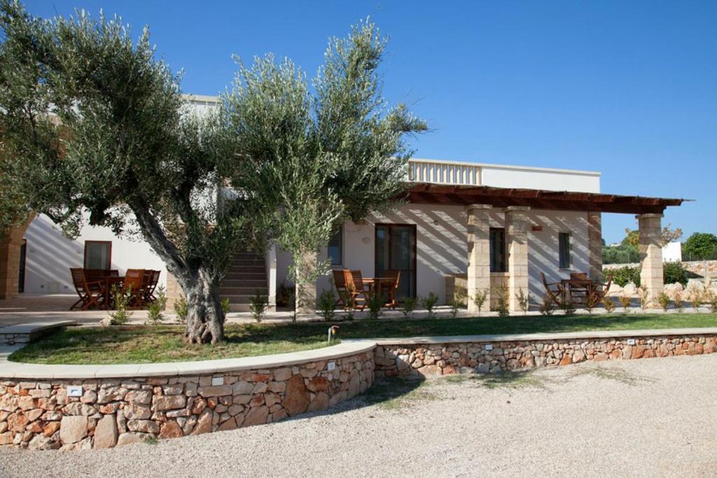 una casa con un árbol y una pared de piedra en Agriturismo Amaranto, en Marina di Pescoluse