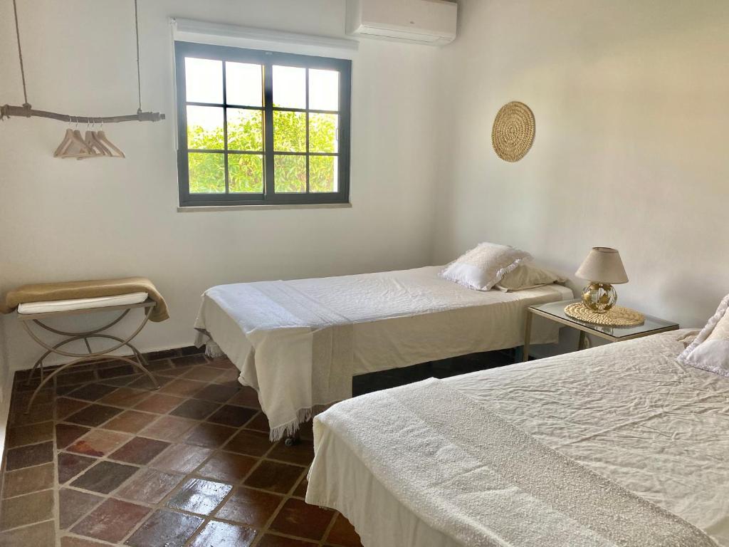 Habitación con 2 camas y ventana en Casa Pedra Rosa - VINHAS de NEXE en Faro