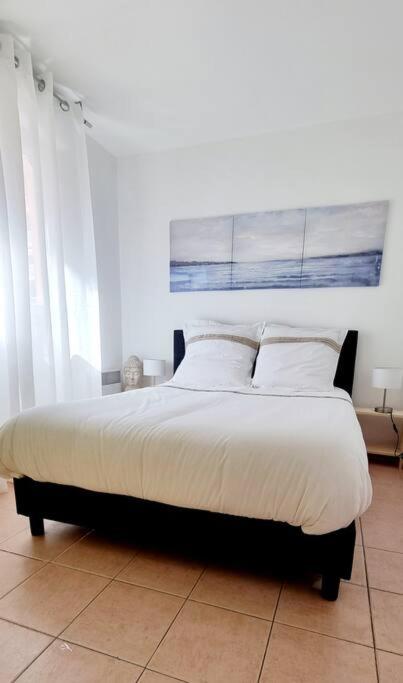 une chambre avec un grand lit avec des draps et des oreillers blancs dans l'établissement Charmant 2 pieces, à Menton