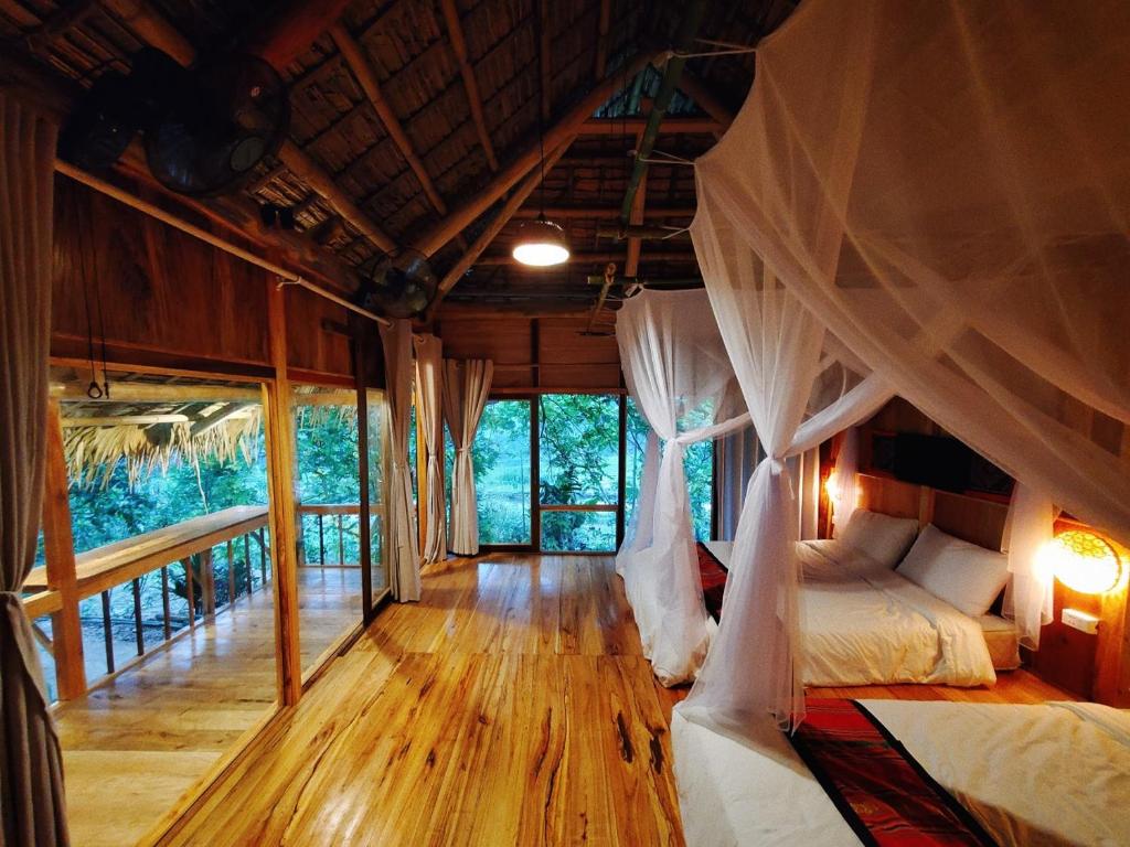 una camera con letto a baldacchino e tende di Pu Luong Thai House - Tai Dam Homestay a Hương Bá Thước