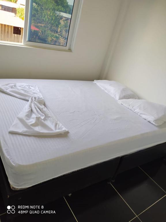 Una cama blanca con una toalla encima. en Apartamentos Olaya!, en Bahía Solano
