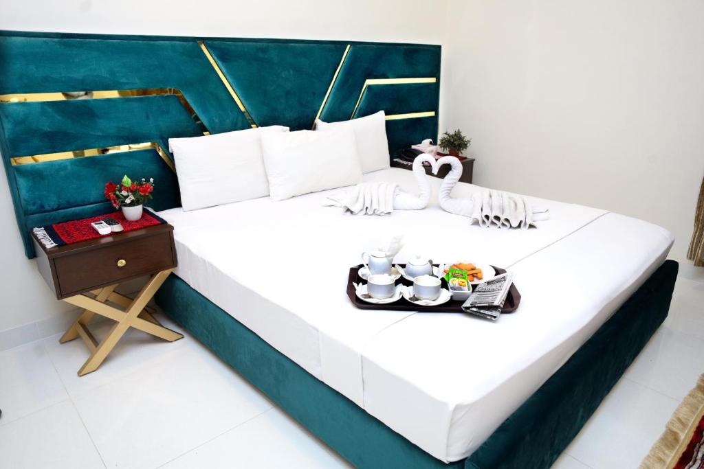 a large white bed with a tray of food on it at Royalton Inn Hotel - Gulberg in Lahore