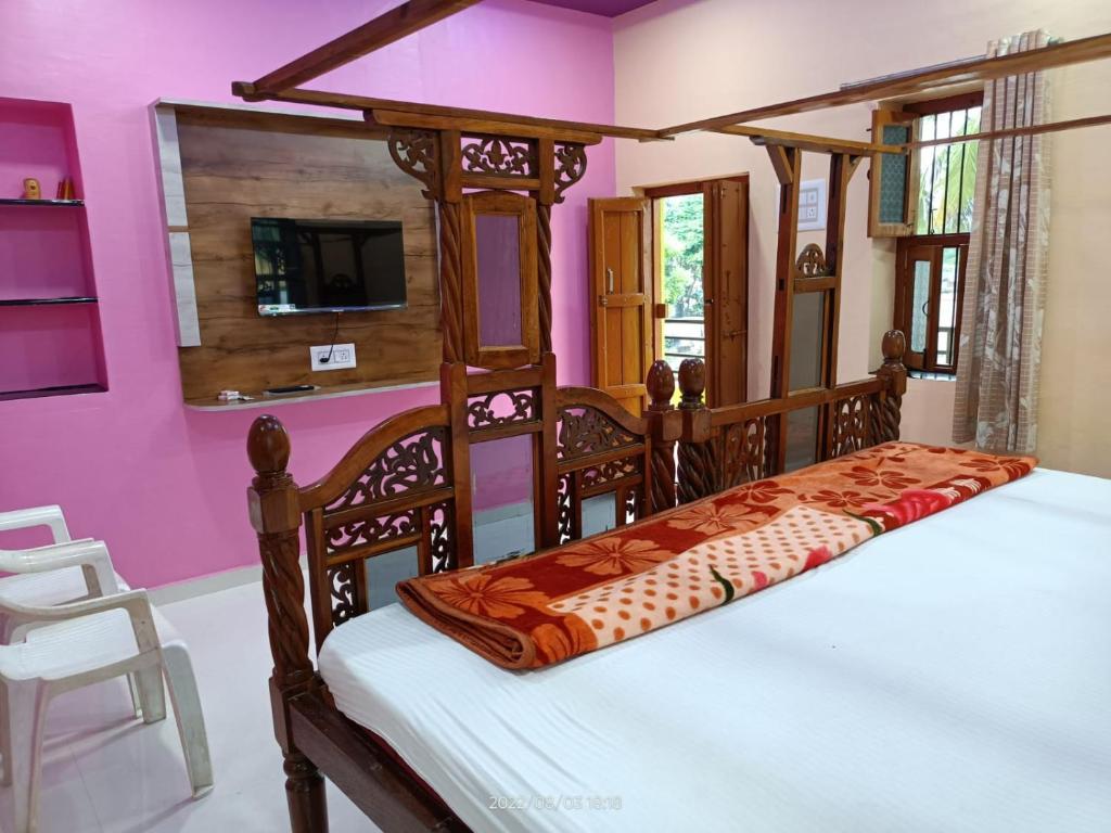 Abhi Homestay Hampi في هامبي: غرفة نوم بسرير خشبي في غرفة