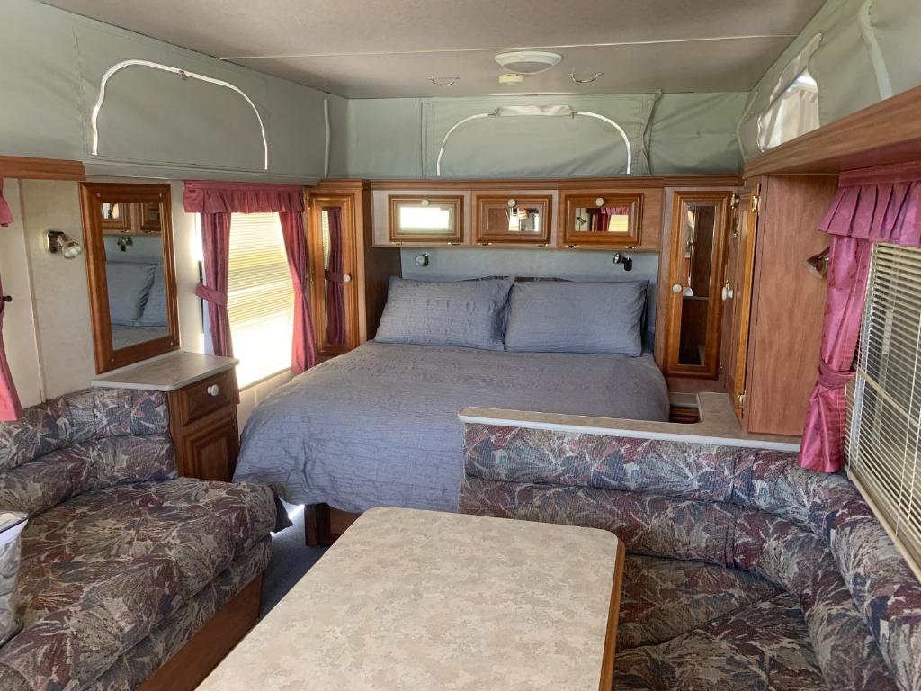 a bedroom in an rv with a bed and a couch at Standown Park Caravan retreat in Goomboorian