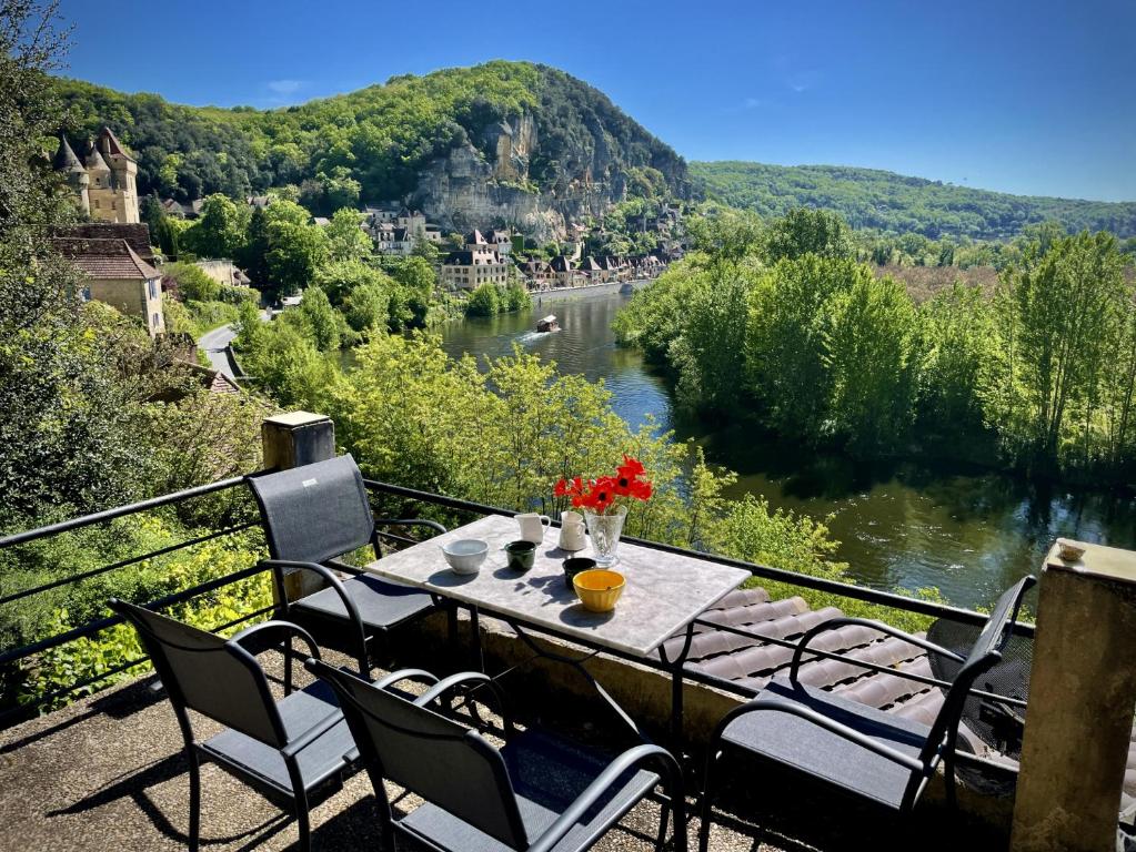 una mesa y sillas con vistas al río en Le Mirador - Splendide vue sur la Roque-Gageac en Vézac