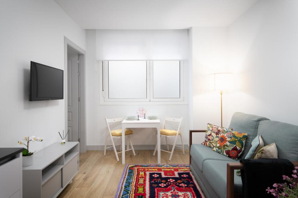 un soggiorno con un divano e un tavolo di Apartamentos La Gringa Centro Gijon II Obra nueva con posibilidad de Parking a Gijón