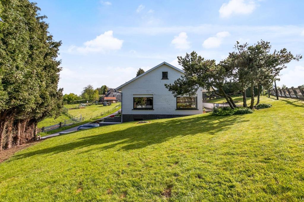 a white house on a hill with a green yard at Vakantiehuis 't Leideveld in Maarkedal