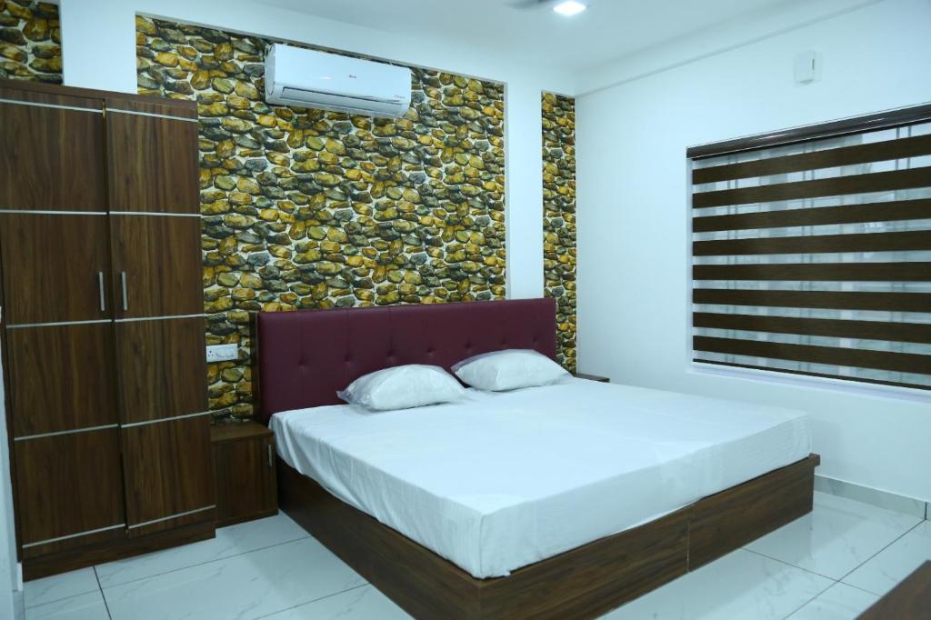 a bedroom with a bed and a stone wall at Kurianplackal Residency in Alwaye