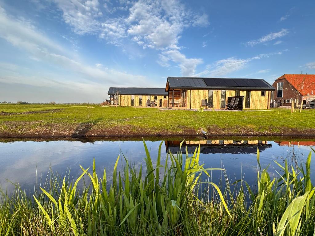 an old barn sits next to a body of water at Gastenverblijf De Natureluur in Noorden