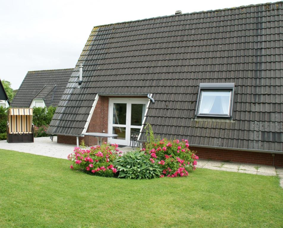a house with a window and flowers in the yard at Ferienhaus Nicole in Neuharlingersiel
