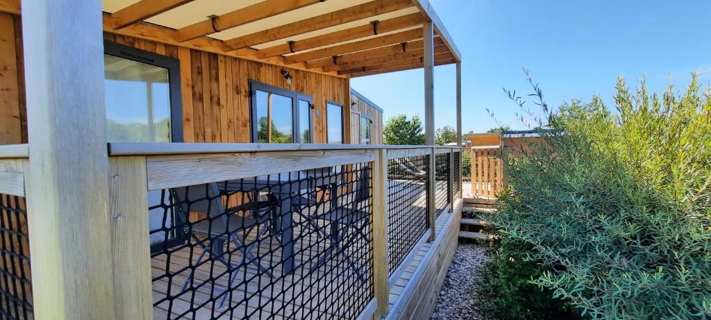 a wooden building with a fence on a deck at Le Village de Cottages - Le Pôle du Cheval et de l'Âne in Lignières