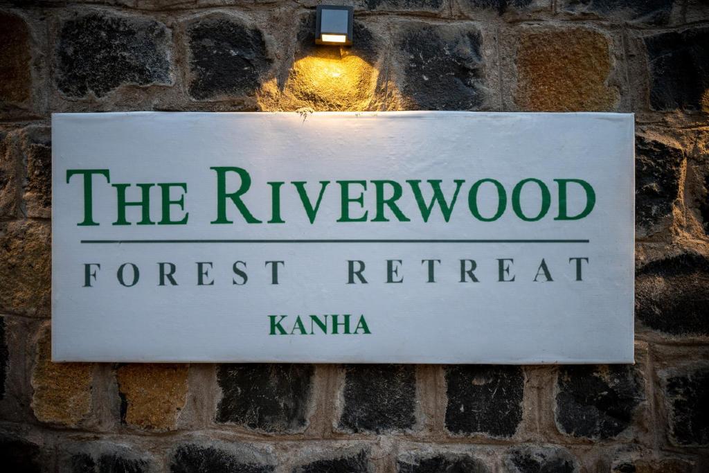 una señal para el retiro del bosque remarcado colgando de una pared de ladrillo en The Riverwood Forest Retreat - Kanha, en Kānha