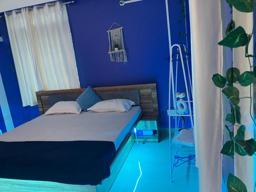 a blue bedroom with a bed and a plant at Casa Felice Jonak in Jorhāt