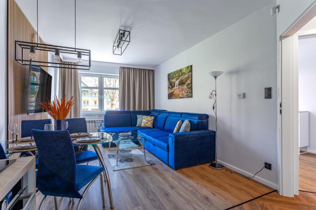 Apart-Invest Apartament Latte في شكلارسكا بوريبا: غرفة معيشة مع أريكة زرقاء وطاولة